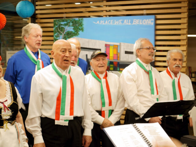 italian choir performing in front of painting a place we all belong