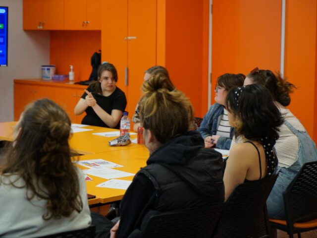 teenagers sitting in orange room in discussion during class