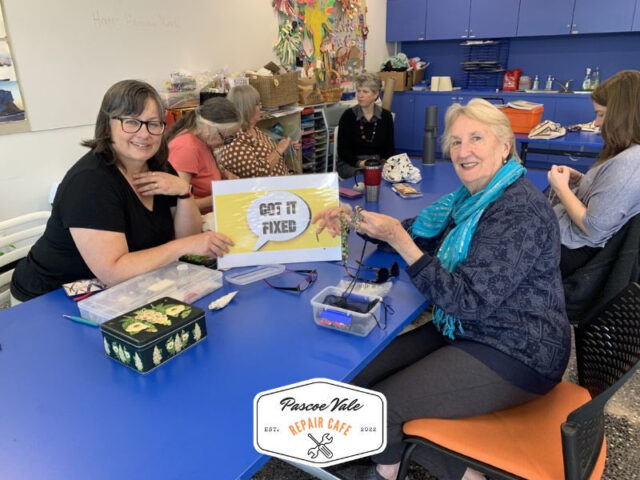 women holding yellow got it fixed sign at pascoe vale repair cafe